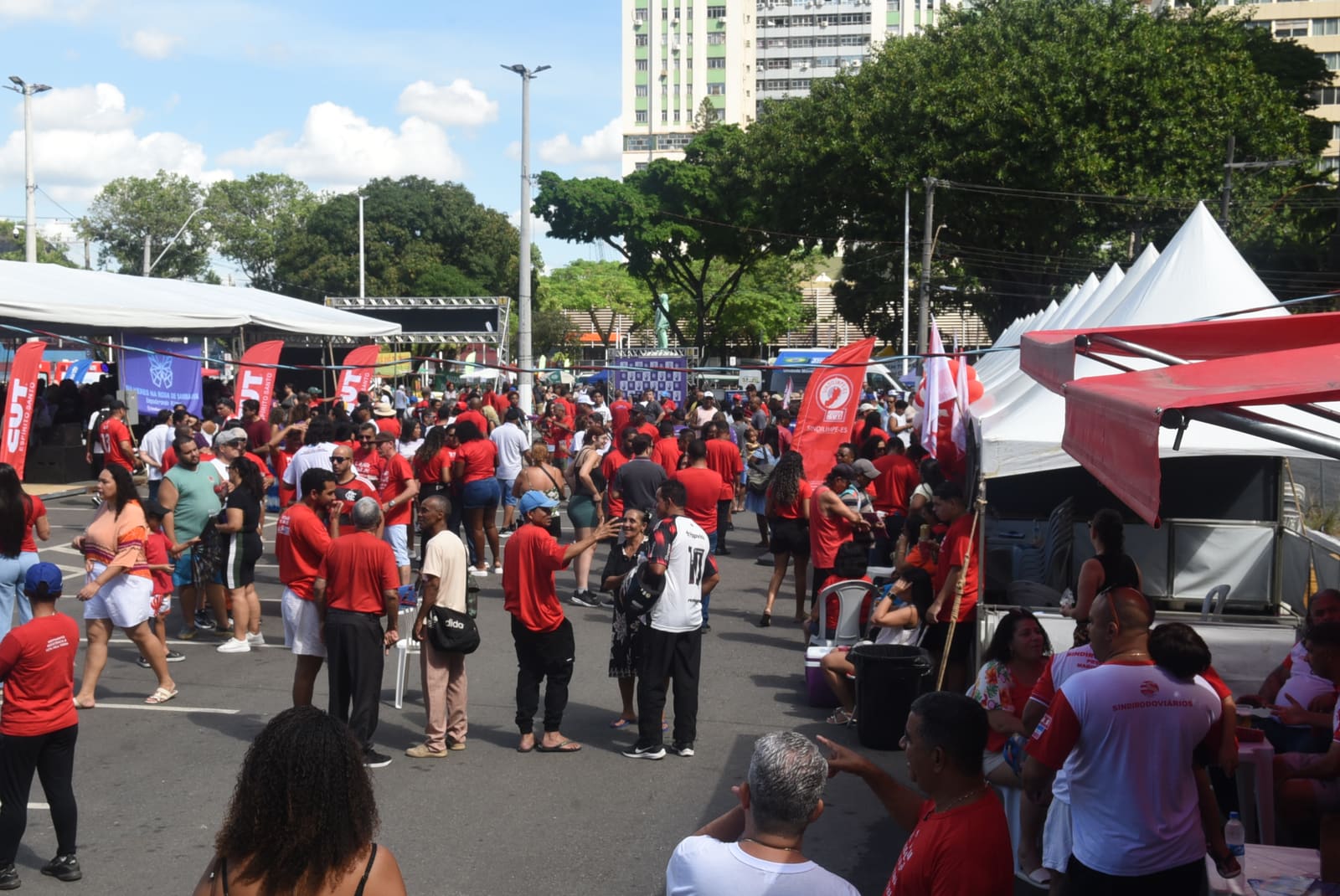 Evento de celebração do Dia do Trabalhador com pessoas assistindo ao samba na Praça Getúlio Vargas.